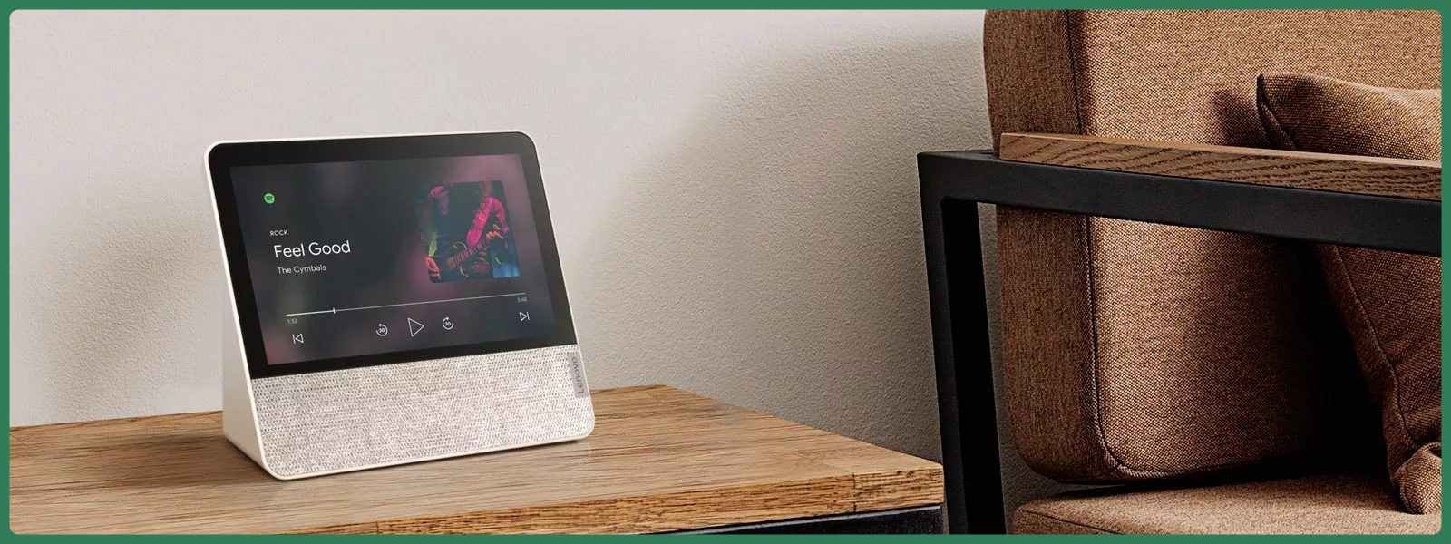 Lenovo Smart Display 7 A smart display rests on a wooden table beside a brown sofa, showing a music player interface with the song "Feel Good." The scene is cozy and modern.